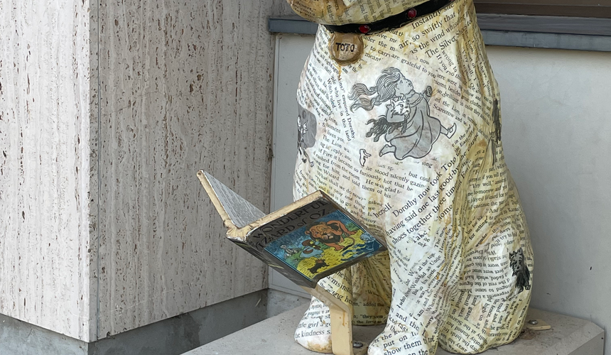 Toto statue covered in pages with red glasses and an open book