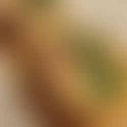 Fried green tomatoes with a shrimp on top of it covered with a yellow sauce.