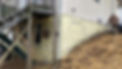 Man working on a house foundation; signs of structural stress visible.