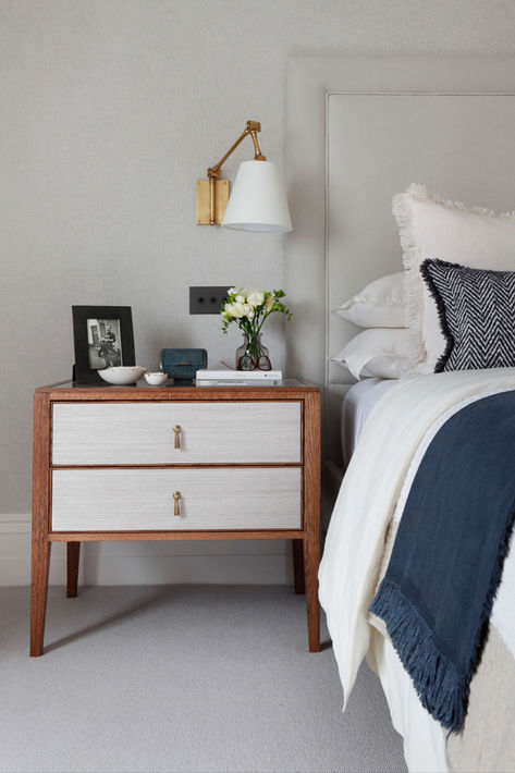 Kingsize bed with off-white linen and navy blue sheets_blue ottoman_wooden bedside tables_bronze wall lights_interior design by Catherine Wilman