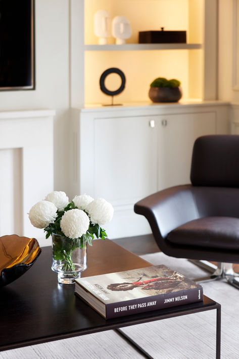 Apartment TV room with brown leather armchair and dark wood coffee table - an interior design project in Kensington by Catherine Wilman
