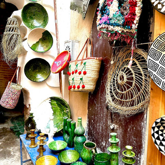 Moroccan ceramic plates and woven bags on display outside a shop in  Marrakesh