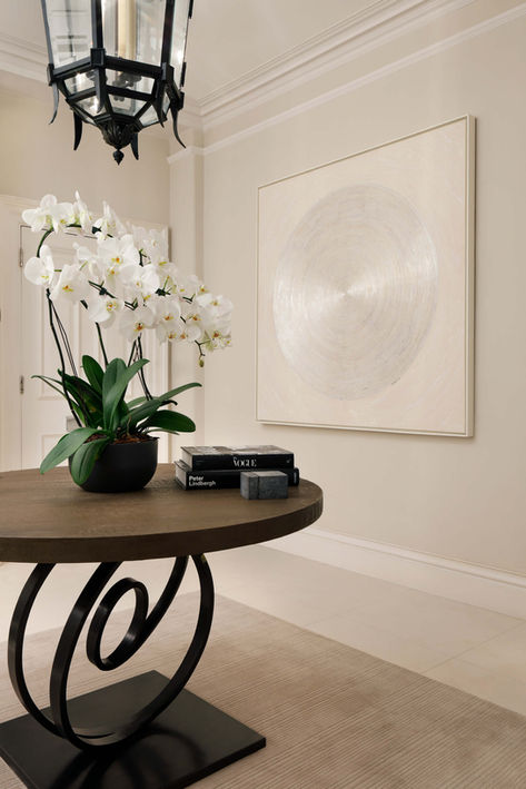 contemporary apartment hallway with modern artwork and dark wood table with flowers - interior design by Catherine Wilman
