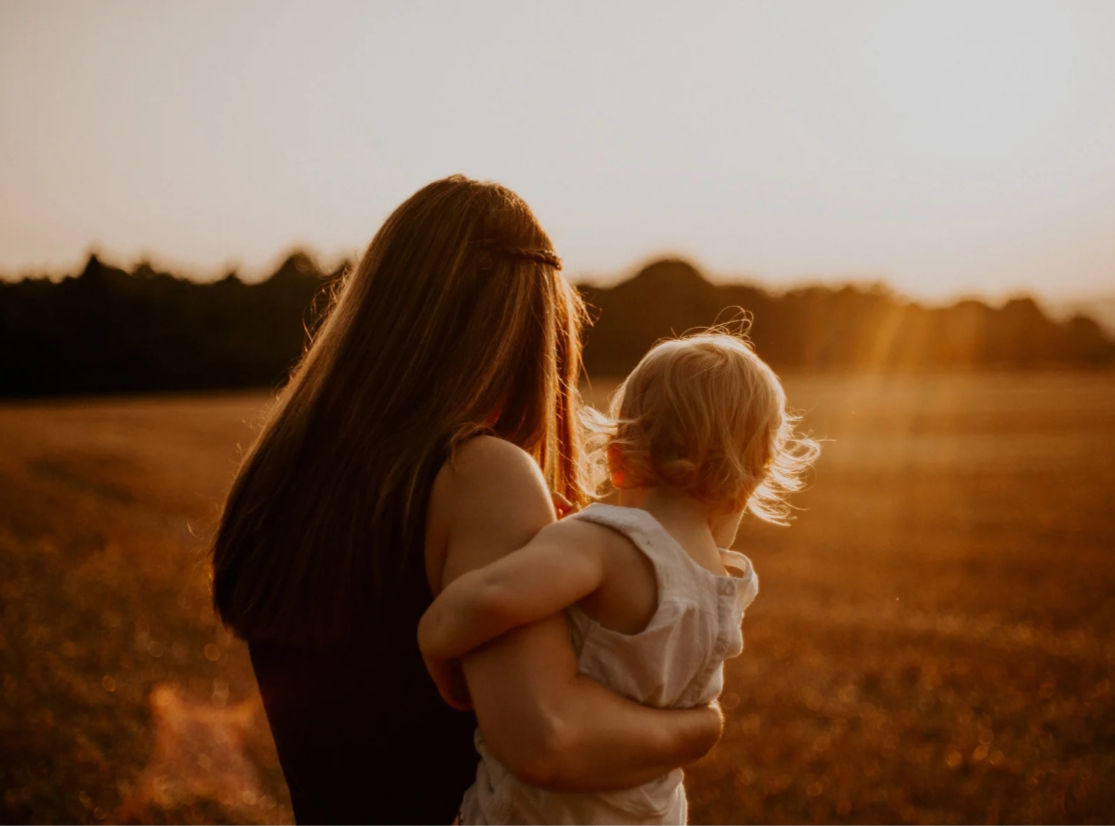 Mutter hält Kind im Sonnenuntergang
