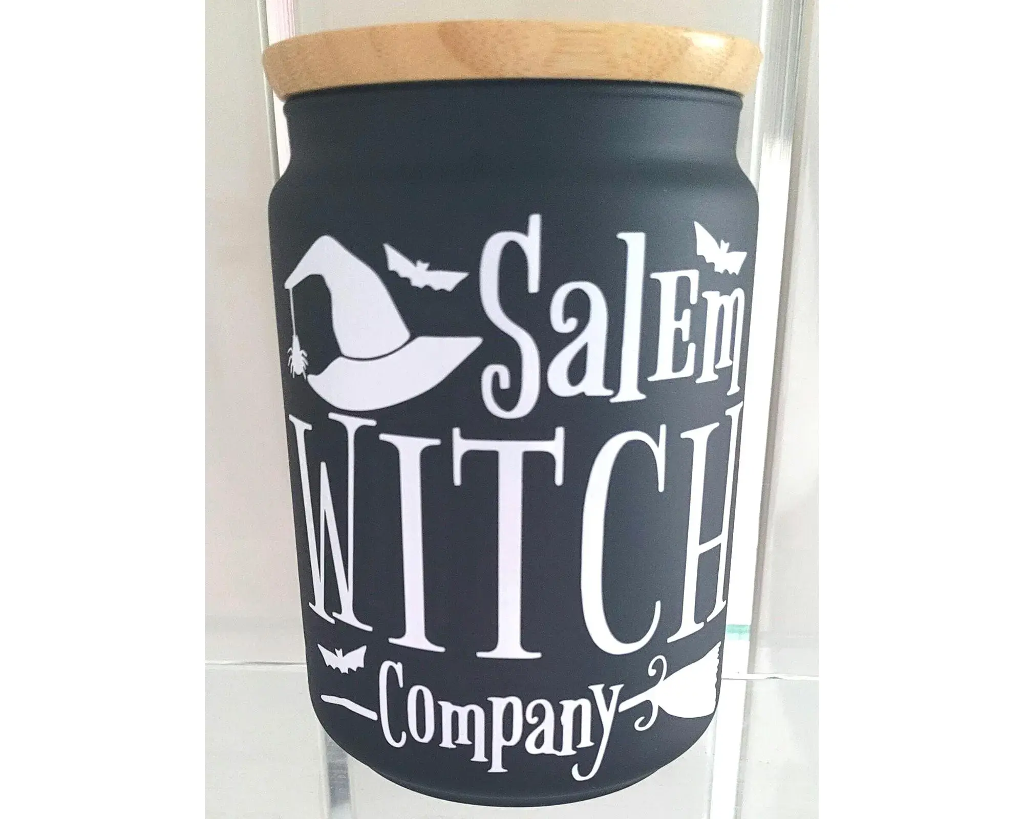 Black glass witchy storage jar with white Salem Witch Company design and bamboo lid.