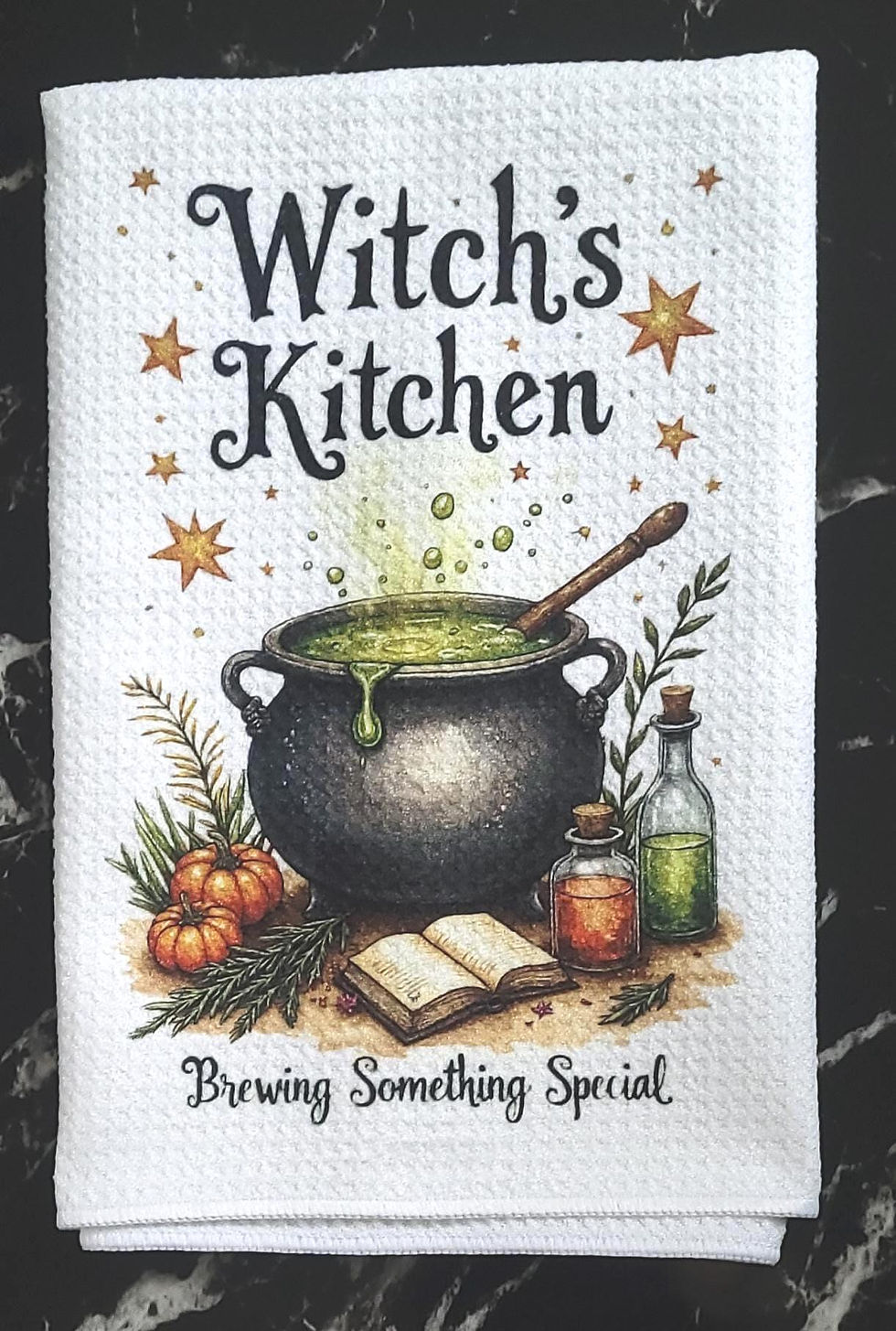 Witchy tea towel with bubbling cauldron and potion bottles reading Witch’s Kitchen.