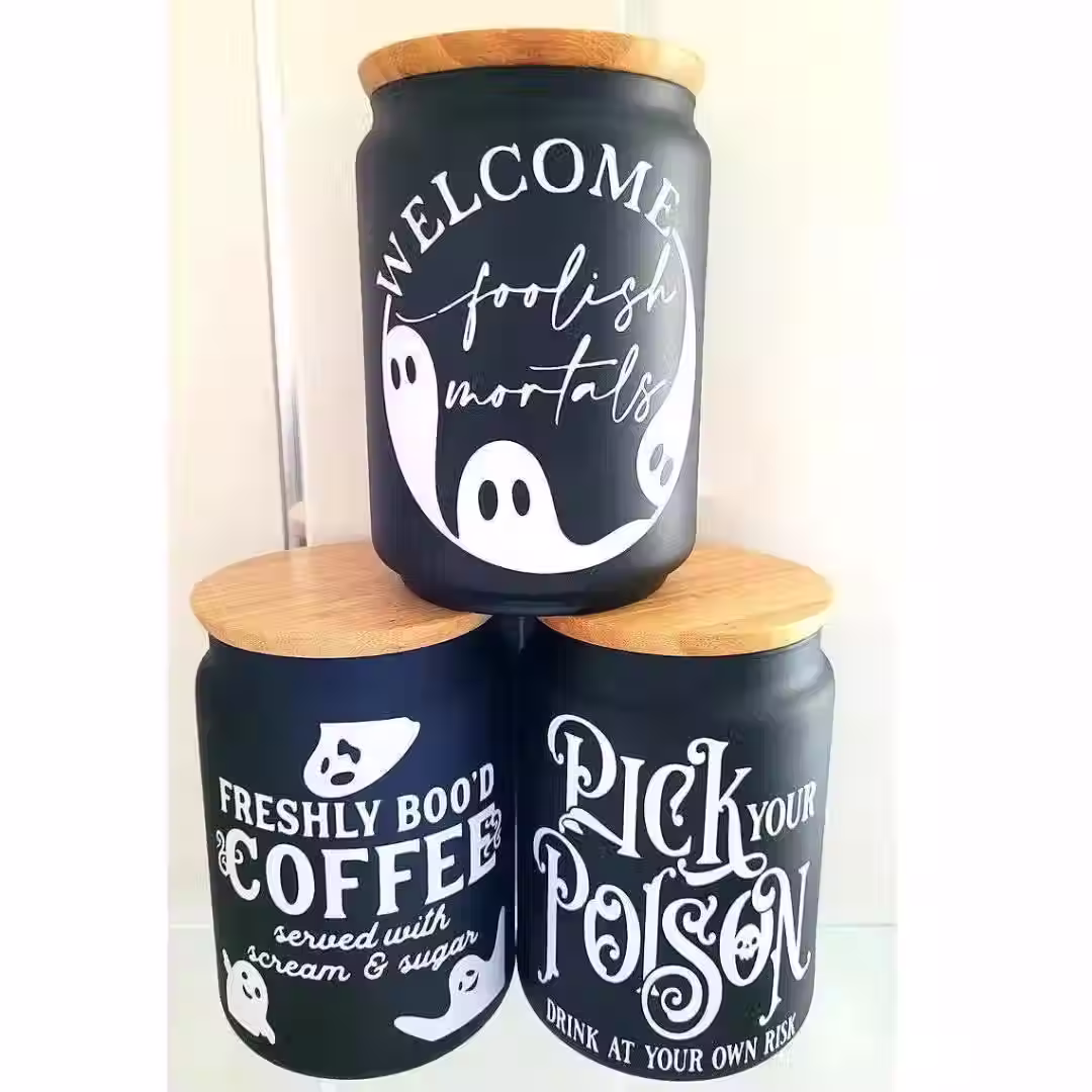 three black jars with white ghost designs reading “Welcome Foolish Mortals,” “Pick Your Poison,” and “Freshly Boo’d Coffee” –