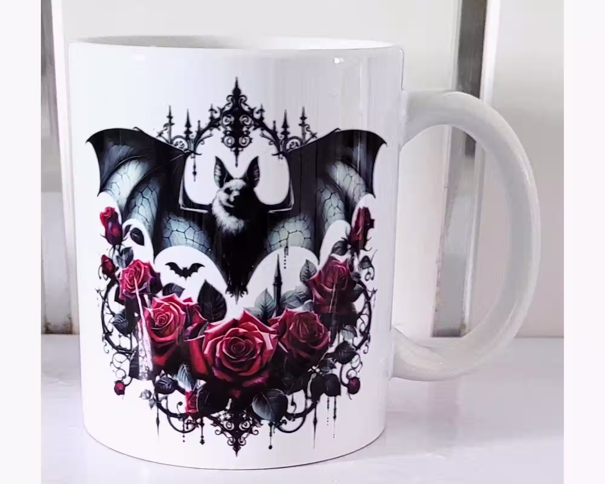 White ceramic mug featuring a gothic bat with black wings and red roses – witchy and gothic coffee cup design.