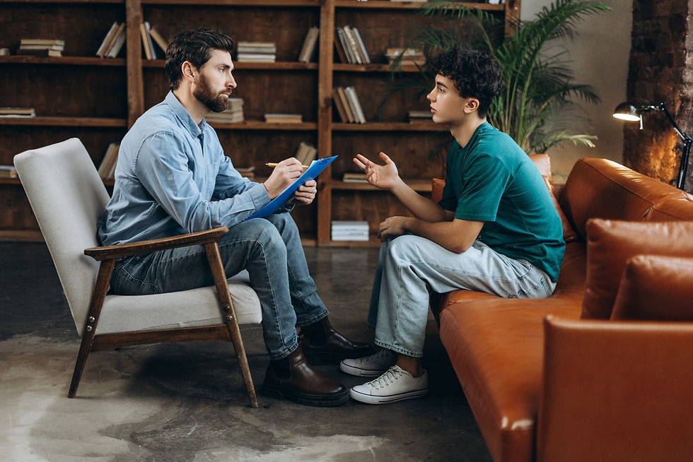 therapist sitting in a chair taking notes with a client seated on a leather couch