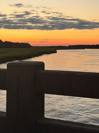 Sunset over a coastal river viewed from a wooden bridge, symbolizing personal growth, new beginnings, creativity, and the courage to start something new.