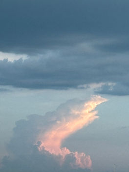 Pink sunlit cloud rising beneath dark storm clouds, symbolizing hope, possibility, personal growth, resilience, and the manifesting mindset.