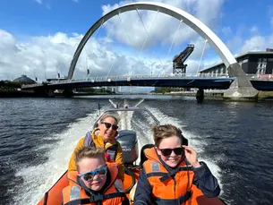 Family on a boat trip on the River Clyde in Glasgow passing under the iconic Clyde Arc bridge.