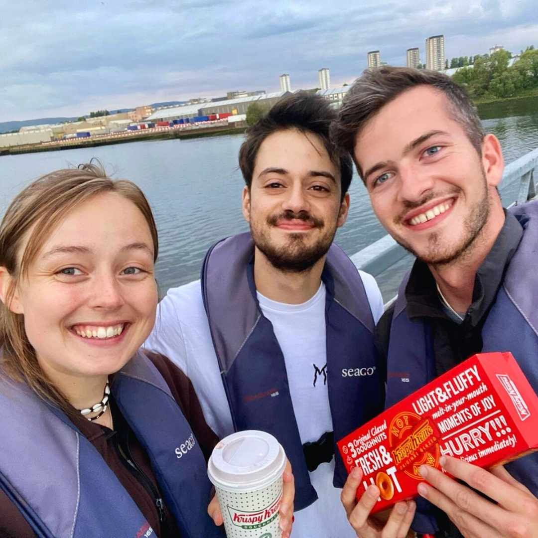Customers holding their Krispy Kreme order and smiling