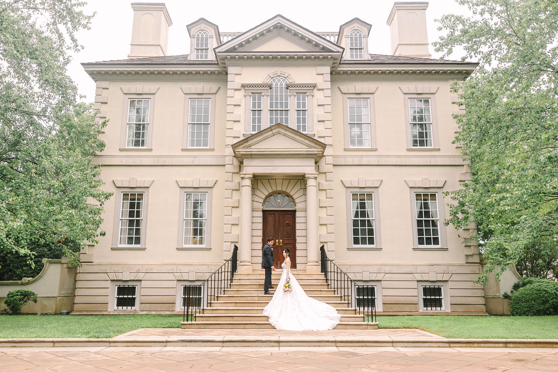A bride and groom ascending steps to their gregorian manor