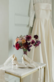 A bridal bouquet and white wedding heels on a table