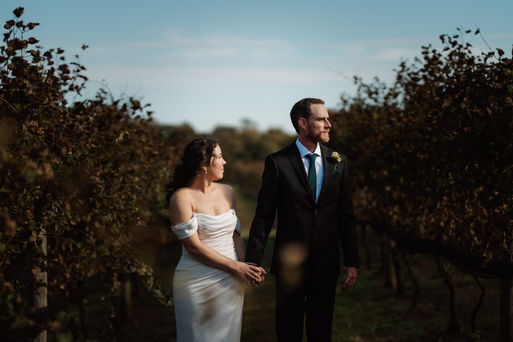 A bride holding her husband by the arm in a vineyard