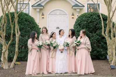A bride with her bridesmaids posing in front of the venue
