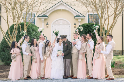 Bride and groom kissing surrounded by wedding party