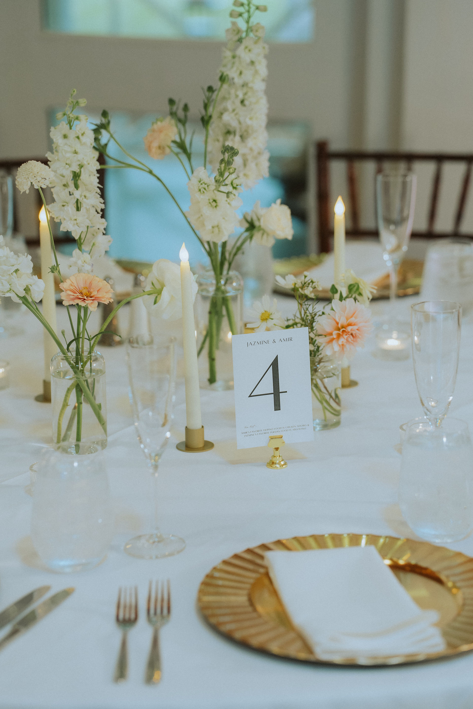 A white table with gold tableware taper candles and flowers