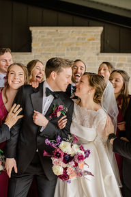 Bride and groom smiling while the wedding party laughs