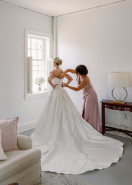 A mom helping her daughter into her wedding dress