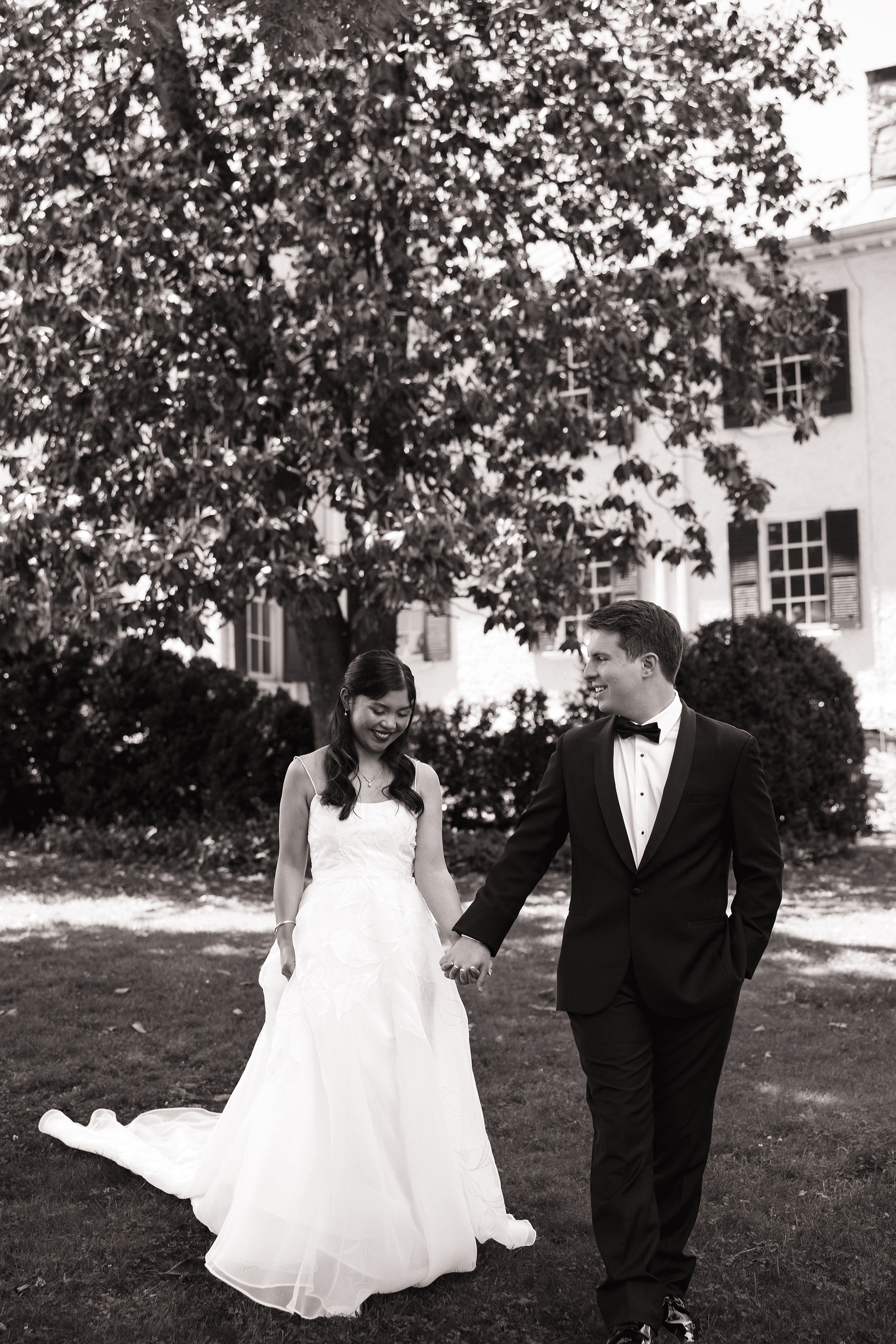 Groom holding bride's hand outside Rust Manor House