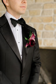 A boutonniere with a burgundy ranunculus and calla lily