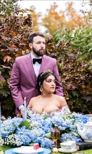 Groom standing behind his wife who is sitting down