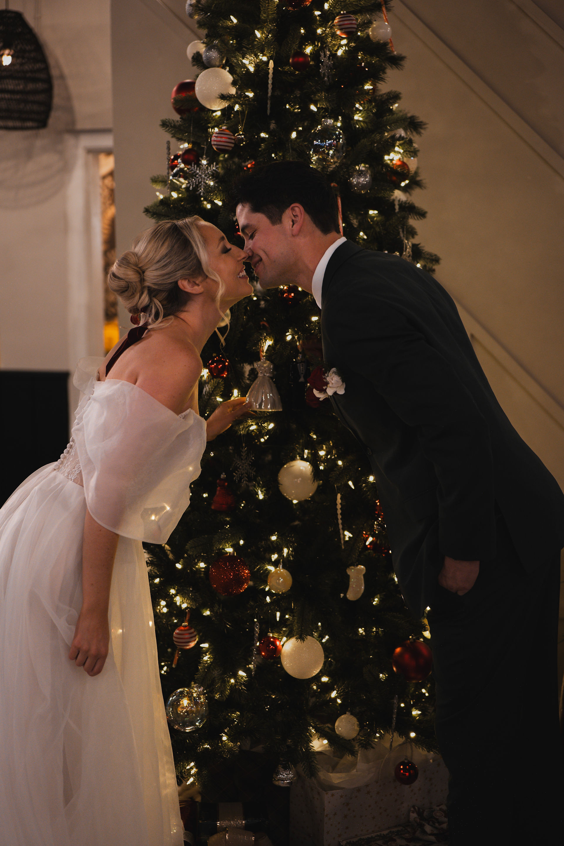 Husband and wife kissing in front of the Christmas tree