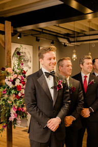 Groom smiling as he watches his bride walk down the aisle