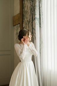 A bride touching her earrings while gazing out a window