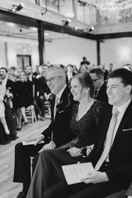 Wedding guests smile as they watch the ceremony