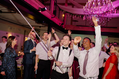 Groom holding up a selfie stick while the guests dance