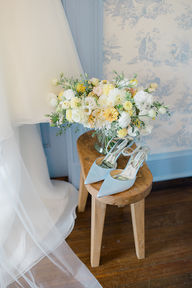 A flower bouquet and blue heels on a table