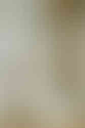 A wedding dress hung by a mirror with bouquet and white shoes