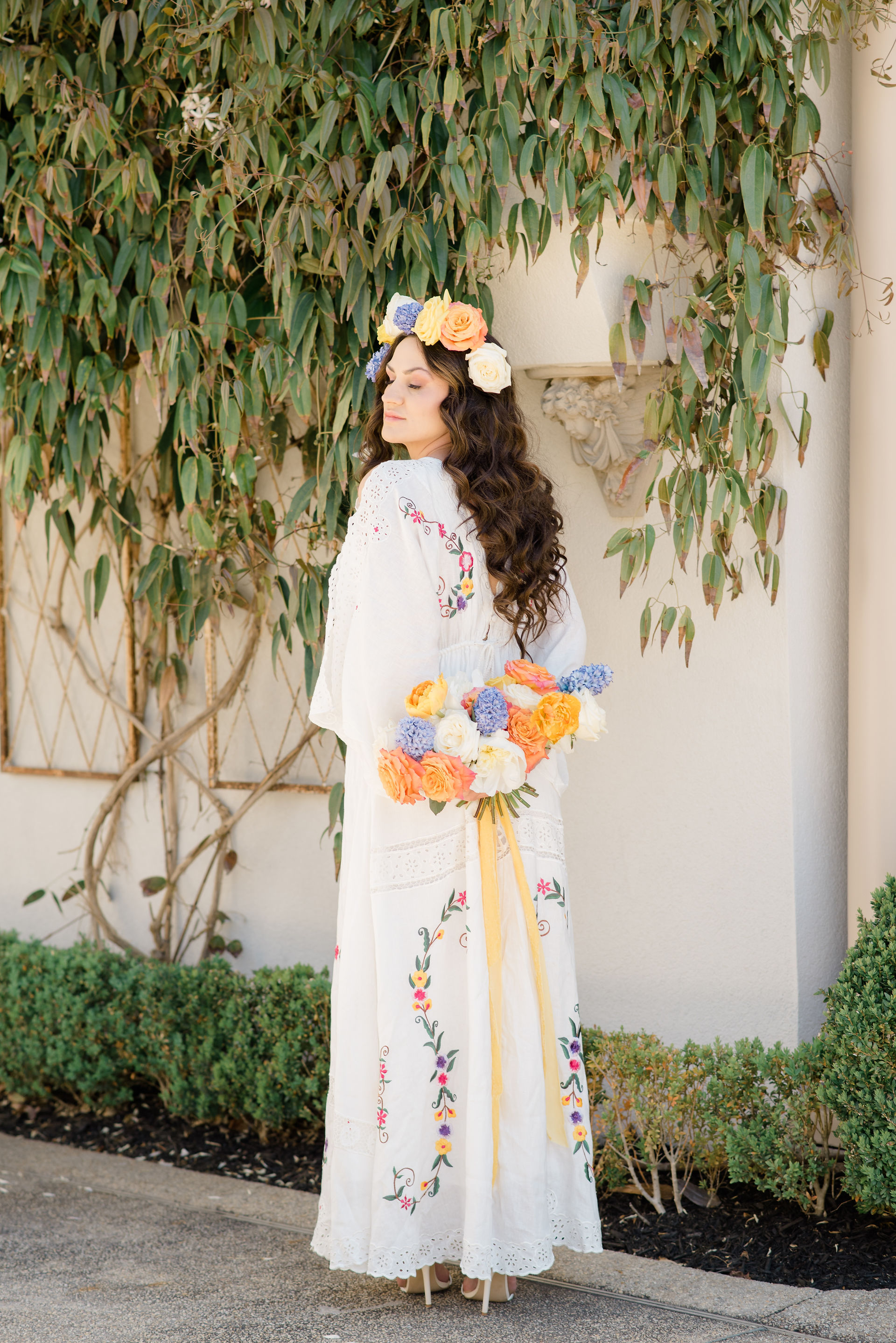 bride holds her bouquet behind her back while closing her eyes