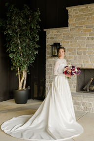 A bride standing by a fireplace with her bouquet