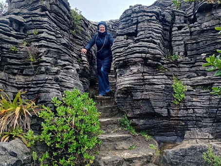 woman standing next to rock formation.