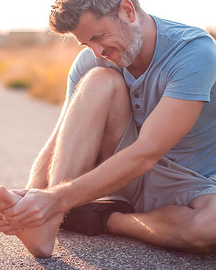 man grabbing his foot and ankle in pain
