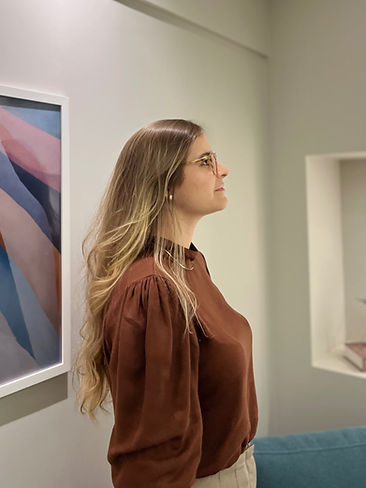 Imagem de Luiza (mulher branca, usando óculos e com cabelos loiros e longos) posicionada de perfil