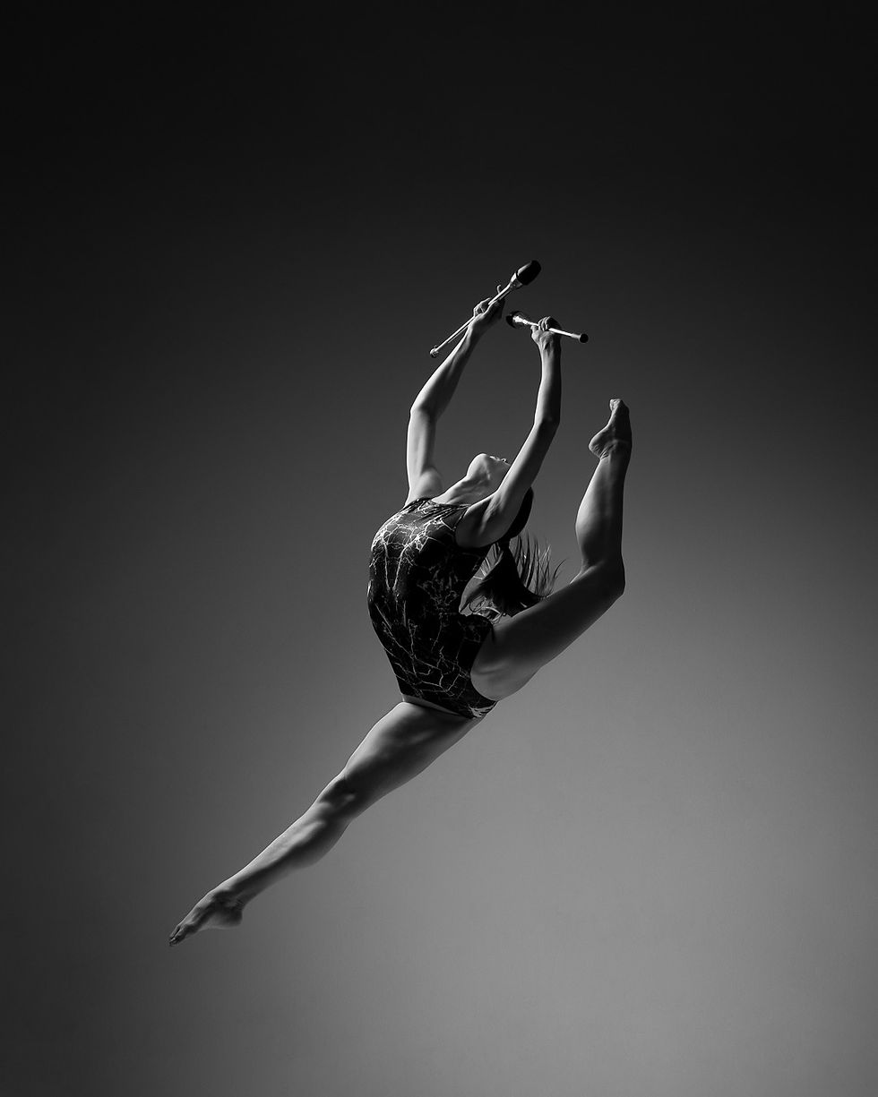 Rhythmische Sportgymnastin im Sprung mit Keulen