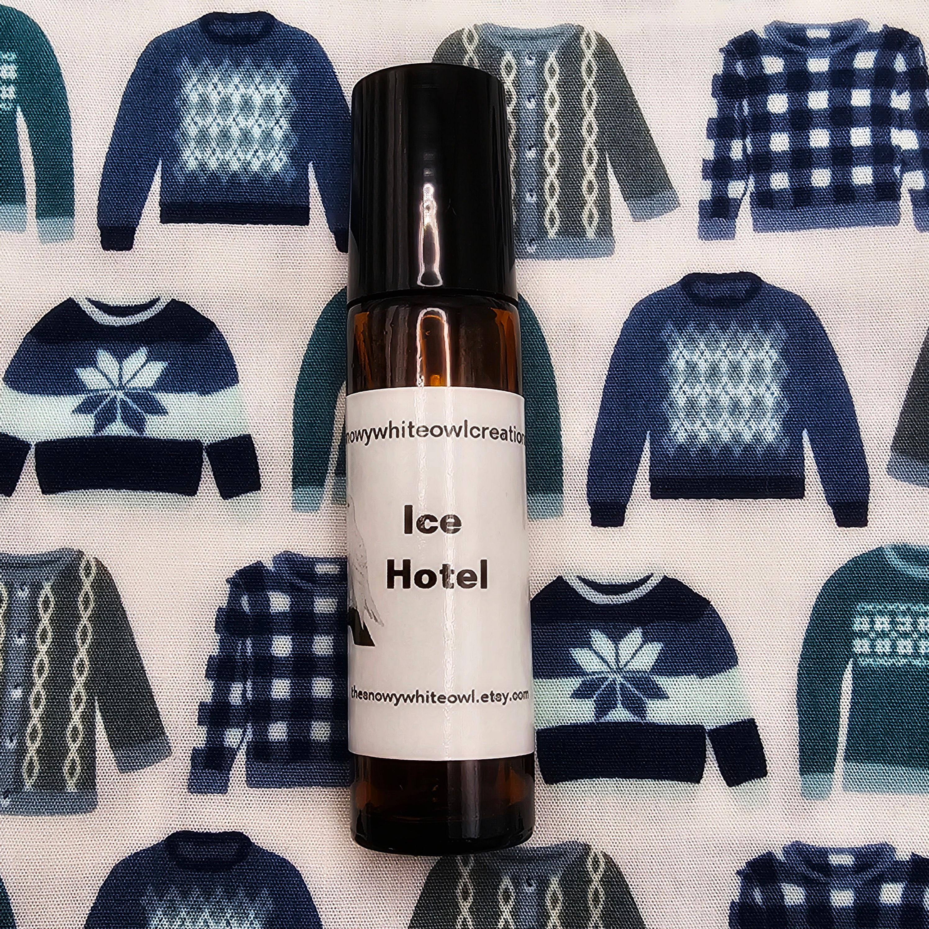 ice hotel perfume oil-amber apothecary bottle-roll on applicator-fabric background of sweaters