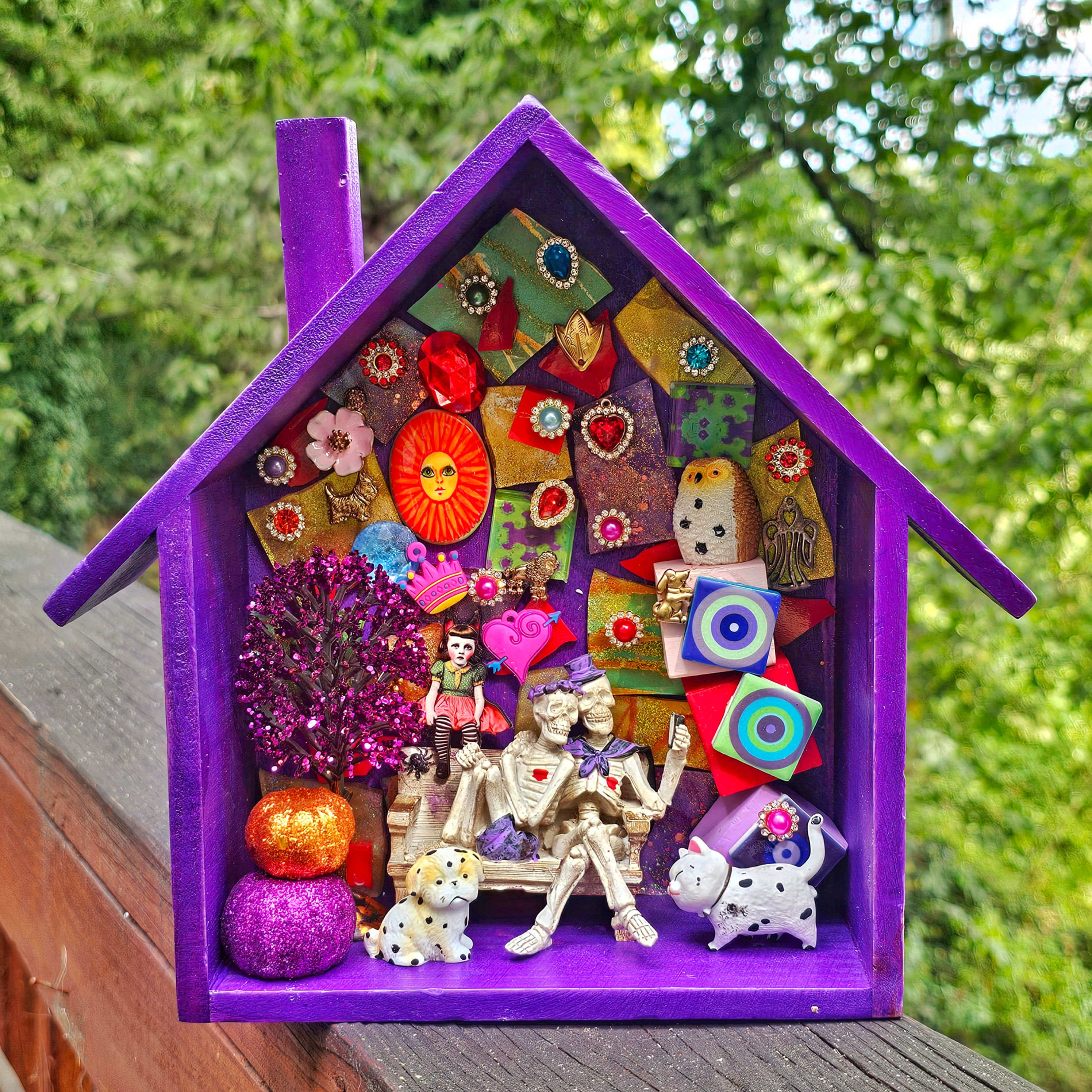 2 skeletons sitting on a bench taking a selfie-owl-cat-dog-spider-pumpkins-purple box-painted blocks-strange girl-glass tiles