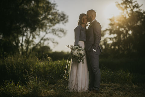 Auf einer Lichtung in der Abenddämmerung steht ein verliebtes Hochzeitspaar.