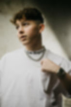 Authentisches Portrait eines jungen Mannes in weißem T-Shirt mit Print, der seine silberne