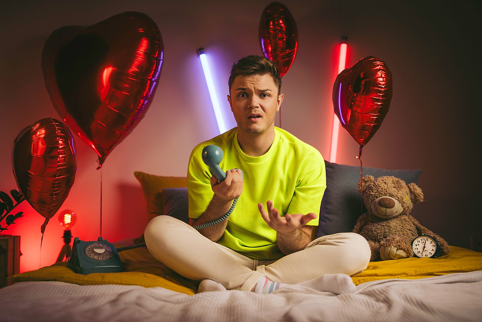 Kevin Neon sitzt auf einem Bett mit einem alten Telefonhörer in der Hand, umgeben von rote