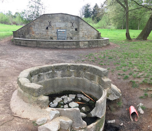 Ursprünglicher Zustand einer gefassten Quelle mit beschädigtem Natursteinbecken – Ausgangssituation vor wasserbaulicher Sanierung