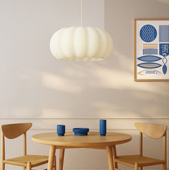 Luminária creme pendurada na mesa de madeira com decoração e ambiente calmo.