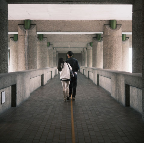 young couple walking through the barbican, london.