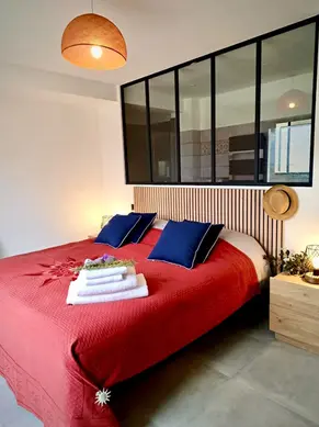 Chambre avec lit double rouge et verrière intérieure - Villa Lavandéa